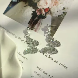 Dettaglio di orecchini lunghi a farfalla con strass scintillanti, gioielli moda estetici.
