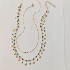 Gold layered choker necklace featuring blue rhinestones and delicate shell pendants detail.