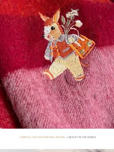 Detailed view of women's burgundy plaid wool scarf featuring cute embroidered rabbit design.