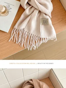 Close-up detail of soft solid color wool winter scarf with fringe edge and label.