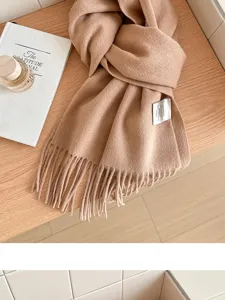 Close-up detail of the soft camel wool scarf with fringe hem, cozy texture and warm fabric.