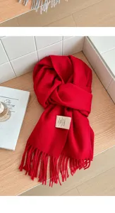 Detail view of a cozy red winter woolen scarf with soft texture and classic tassels.