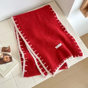 Red knitted winter scarf with white contrast edge, stylish cozy warm apparel for men and women.