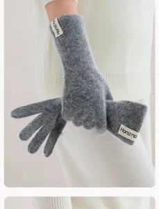 Detailopname van lange grijze harige gebreide handschoenen met handgemaakt label.