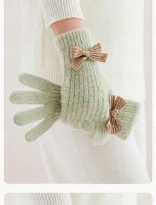 Gros plan de gants tricotés verts avec nœud marron, texture douce pour accessoire d'hiver.