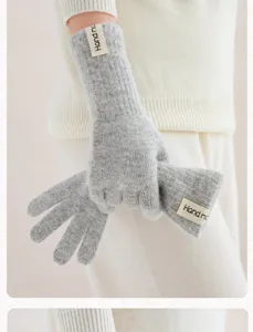 Detailopname van grijze gebreide handschoenen met handgemaakt label voor winterse warmte.