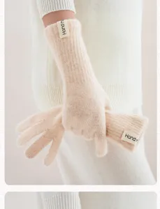 Detailopname van zachte, beige gebreide lange handschoenen met handgemaakt label.