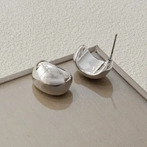Detaillierte Nahaufnahme minimalistischer silberner C-förmiger Ohrringe auf Tablett.