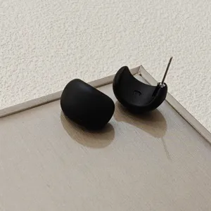 Detailansicht minimalistischer schwarzer C-förmiger Ohrringe mit modernem und glattem Design.