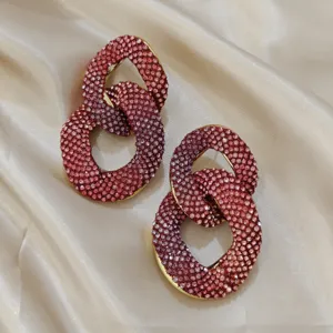 Detailaufnahme von übergroßen funkelnden Strass-Verbindungsring-Ohrringen in Rosa Lila.