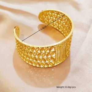 Detaillierte Nahaufnahme des breiten hohlgeschnitzten goldenen Armreifs im ethnischen Retro-Stil.