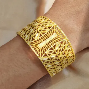 Nahaufnahme eines breiten goldenen Armreifs im Vintage-Stil mit filigranen geometrischen Mustern.