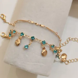 Detailed shot of double layer gold necklace with blue rhinestones and shell charms.