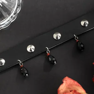 Close-up detail of dark gothic leather choker with metal spikes and black teardrop charms.
