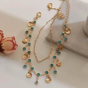 Gold layered necklace detail featuring blue crystal rhinestones and shell charms, elegant design.