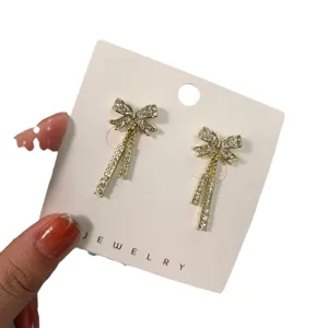 Eleganti orecchini pendenti con fiocco in strass dorati, gioielli lunghi scintillanti donna.