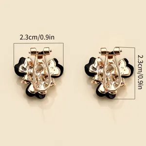 Detail view of stylish four-leaf clover clip earrings with black inlay and golden finish.