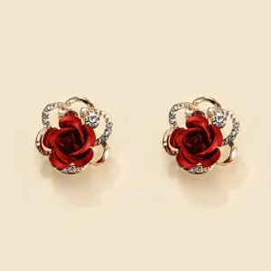 Close-up detail view of elegant red rose earrings with sparkling rhinestones and gold finish.