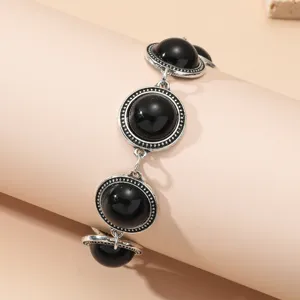Close-up view of vintage silver-toned chain bracelet featuring black round stone details.