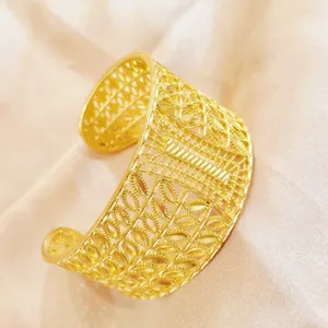 Nahaufnahme eines breiten, goldenen Armreifs mit filigranem, orientalischem Blumenmuster.