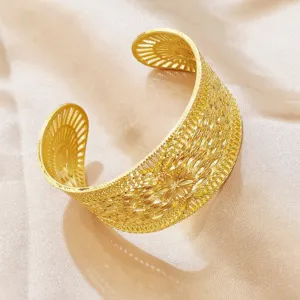 Nahaufnahme des filigranen, ausgehöhlten Goldarmbands mit floralem Motiv, elegante Details.