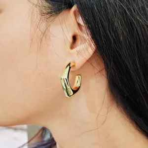 Gros plan détaillé de boucles d'oreilles créoles dorées élégantes et brillantes en métal.