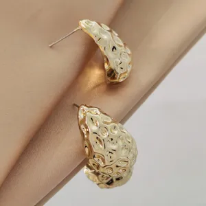 Detailed close-up of modern irregular waterdrop hammered gold stud earrings with elegant textured finish.