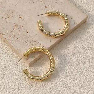 Gold bamboo hoop earrings detail shot showcasing unique textured geometric fashion jewelry style.
