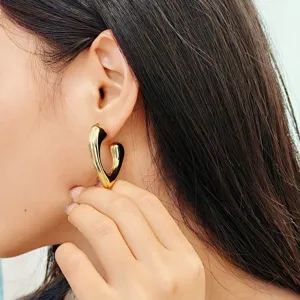 Superbe vue détaillée des boucles d'oreilles créoles cœur dorées portées élégamment.