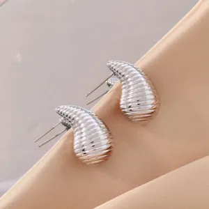 Detailed view of trendy ribbed teardrop stud earrings in silver finish, elegant jewelry piece.