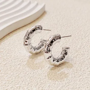 Close-up detail of silver bamboo textured hoop earrings, showing unique geometric metallic shine.