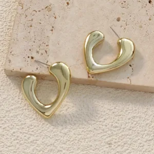 Gros plan detaille de belles boucles d'oreilles creoles coeur en metal dore mode femme