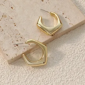 Boucles d'oreilles créoles géométriques dorées, gros plan, design minimaliste quotidien.