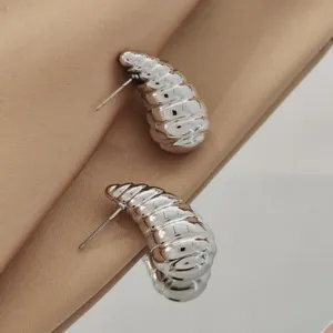 Close-up detail of silver hammered conch stud earrings featuring a unique metallic textured design.