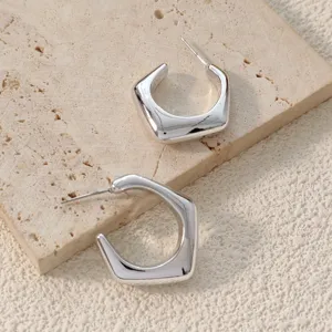 Vue détaillée de boucles d'oreilles créoles géométriques argentées, design minimaliste.