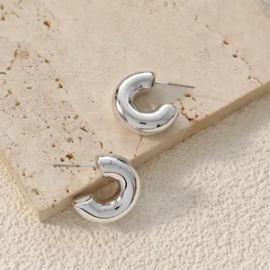 Gros plan boucles d'oreilles créoles épaisses argentées, design en C épuré et poli brillant.