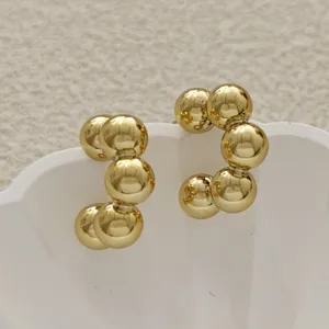 Boucles d'oreilles boules dorées créoles C en détail, bijou géométrique chic et élégant.