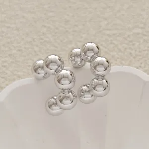 Vue détaillée en gros plan de boucles d'oreilles créoles sphériques en métal argenté poli.