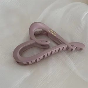 Close-up view of a large matte mauve heart-shaped hair claw clip with delicate gold branding.