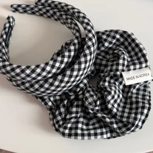 Close-up detail view of black and white gingham headband and scrunchie hair accessories set.