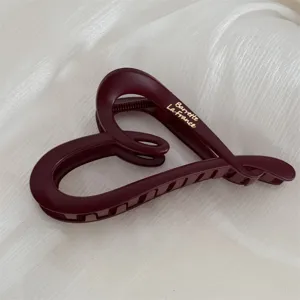 Matte burgundy heart-shaped hair claw clip with elegant gold typography for thick hair styling.