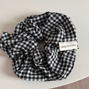 Detailed closeup of a classic black and white gingham fabric hair scrunchie with cute label.