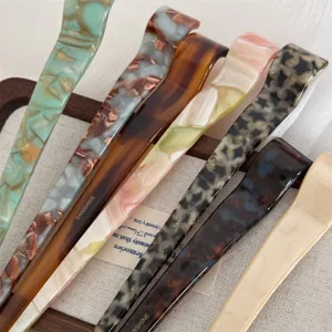 Close-up detail of stylish acetate hair sticks featuring various elegant tortoiseshell marble patterns.