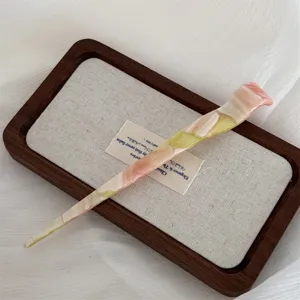 Detail shot of the elegant marbled acetate hair stick resting on a wooden tray.
