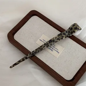 Elegant acetate hair stick detail, vintage tortoiseshell pattern for chic chignon styling.