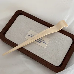 Close-up detail of elegant minimalist beige acetate hair stick, smooth curved design.
