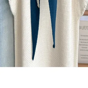Detail van gebreide driehoekige sjaal, zachte witte wollen omslagdoek met blauwe linten.