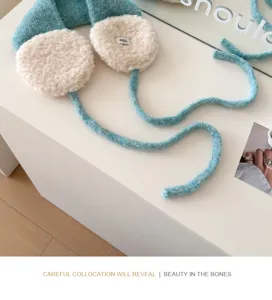 Blue knitted earmuffs detail shot, fluffy plush ear pads with long ties, cozy winter accessory.