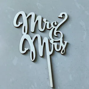 Close-up detail of white wooden Mr and Mrs cake topper, wedding party decoration element.