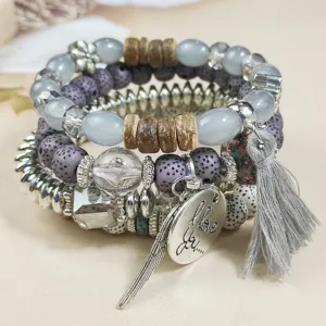 Boho multi-layer beaded stack bracelet detail with metal charm, tassel and crystal stones.
